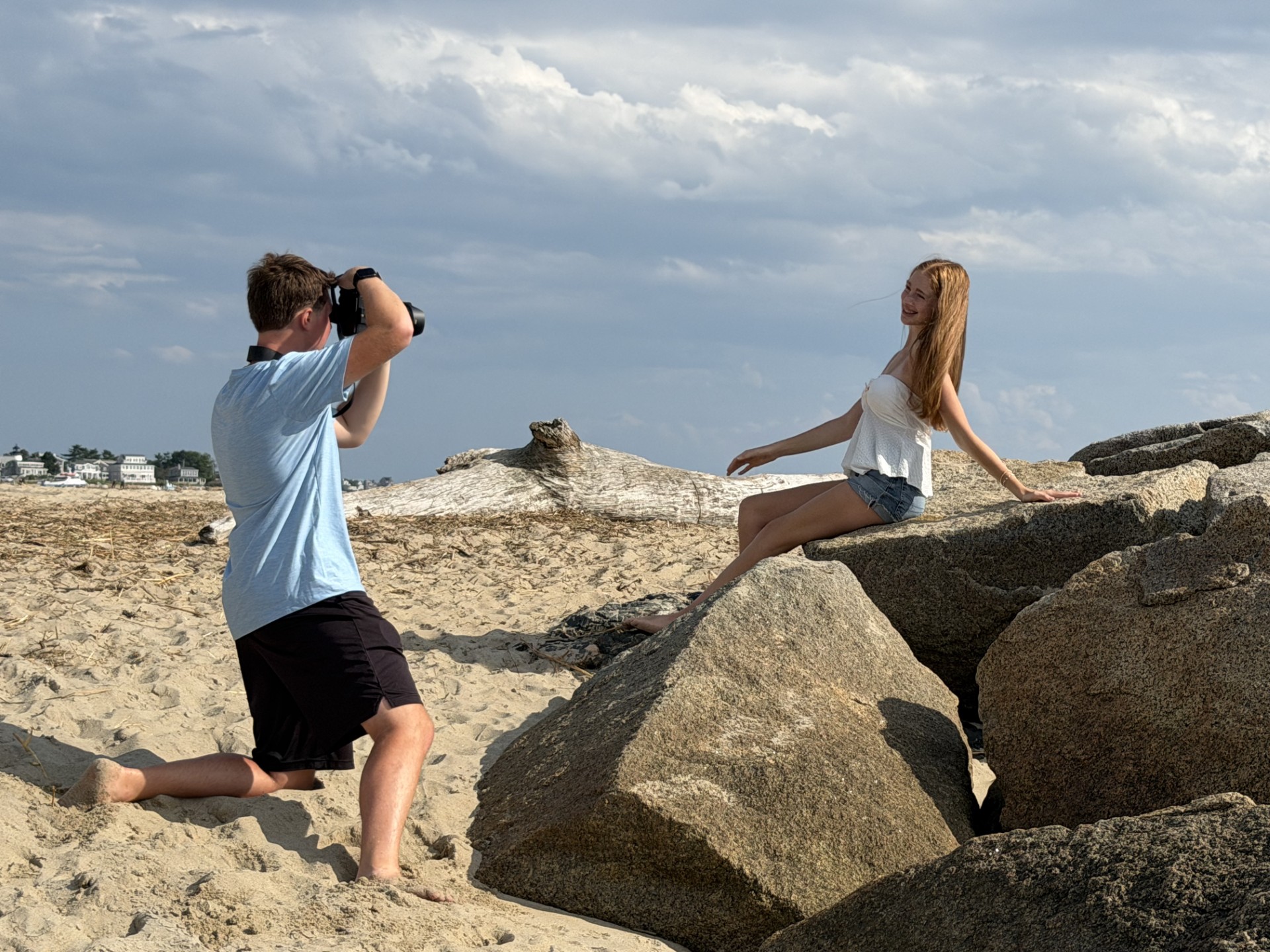 Photographer kneeling on the beach shooting a portrait on the rocks